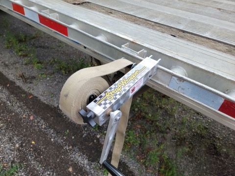 Red clamp knob holding the aluminum Strap Wrapper on the edge of a trailer rail