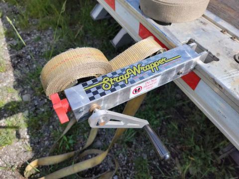Two inch yellow cargo nylon strap wound evenly, hook facing the trailer rail